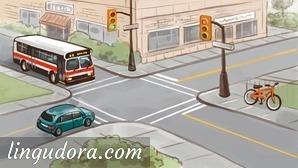 A bus and a car meet at the crossroads. At the opposite corner a bicycle is leaning against a fence. Next to the crossroads there are two traffic lights.